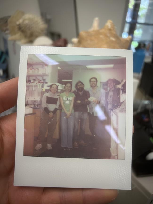 A polaroid photo held up in a lab shows five researchers standing together