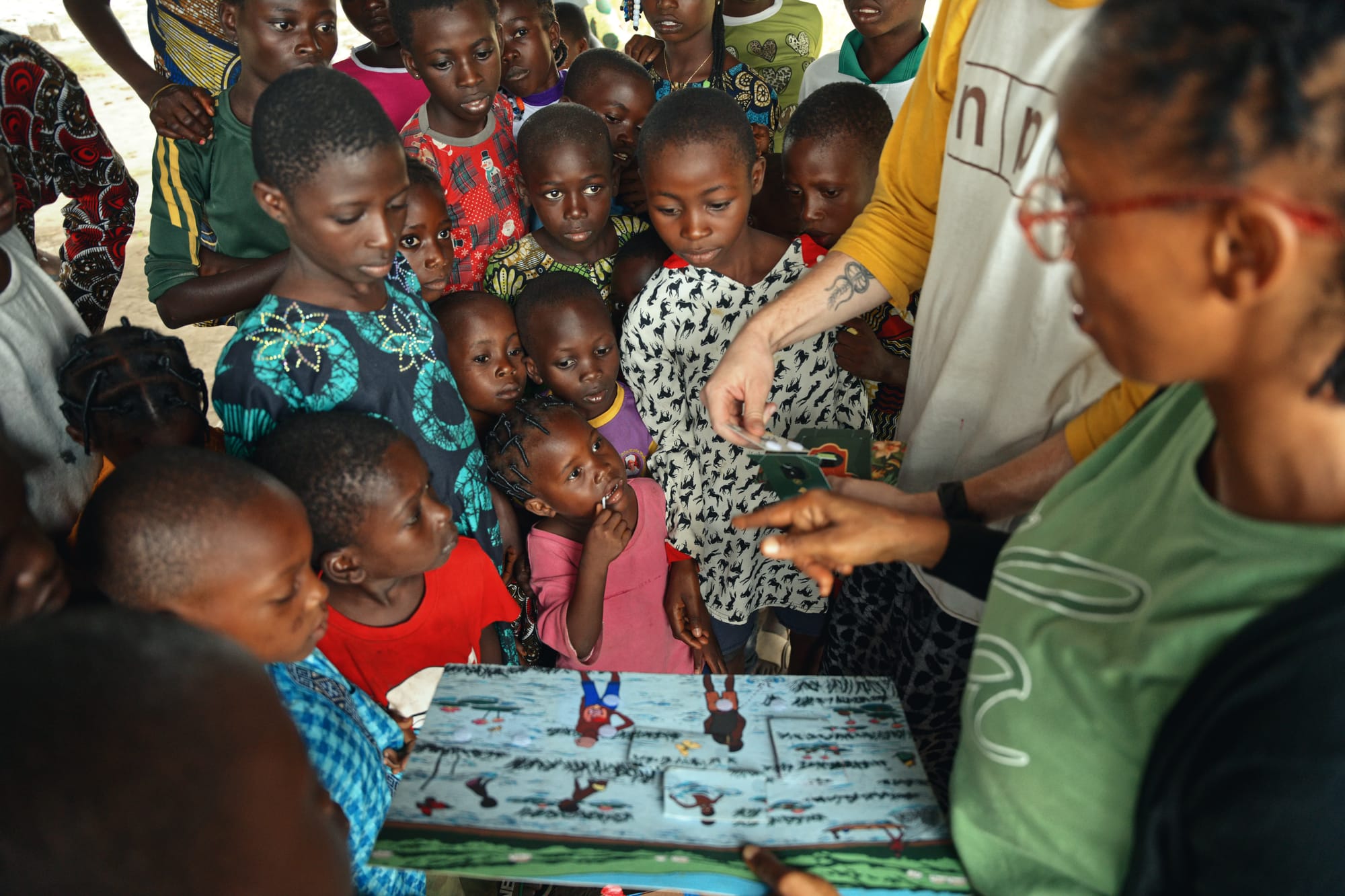 Children crowd around a colorful puzzle as an educator holds a Foldscope over one piece
