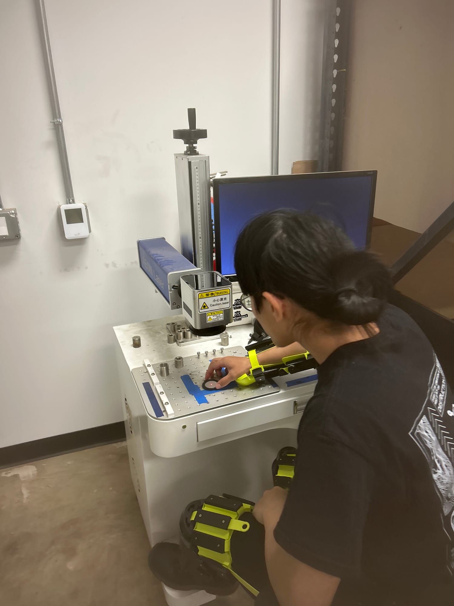 A makerspace member operates a laser cutter at a workstation