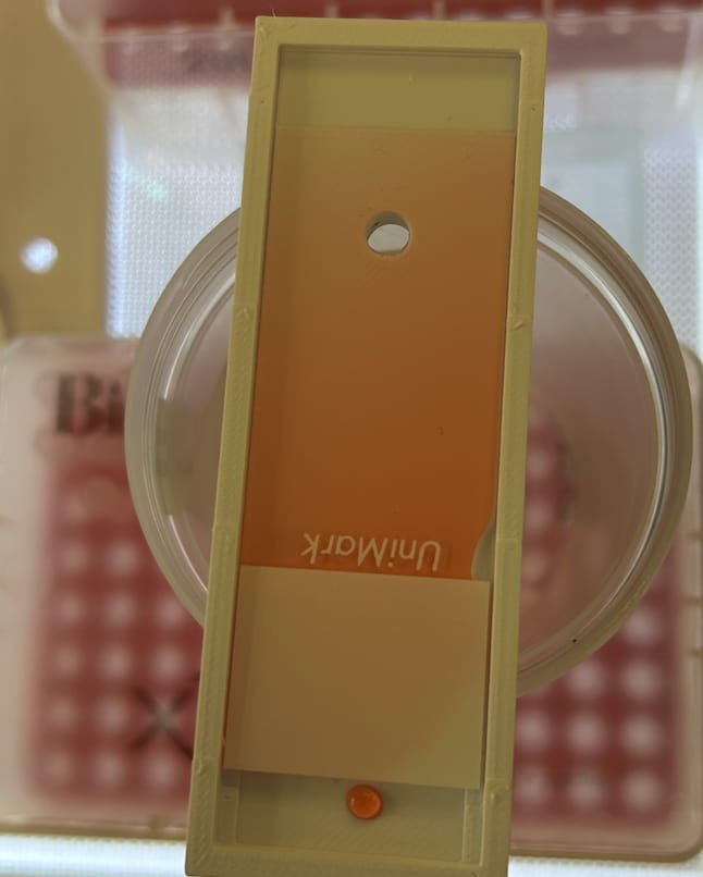A wedge device with red fluid showing its gradient under a glass slide